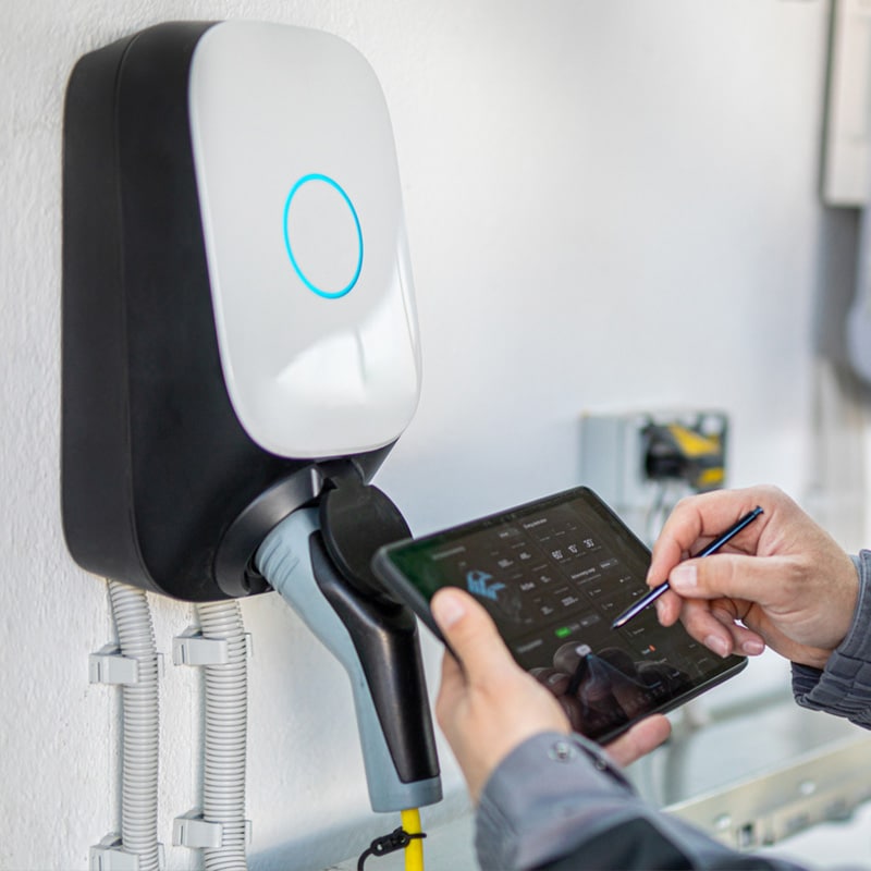 Person using tablet to configure electric vehicle charging station.