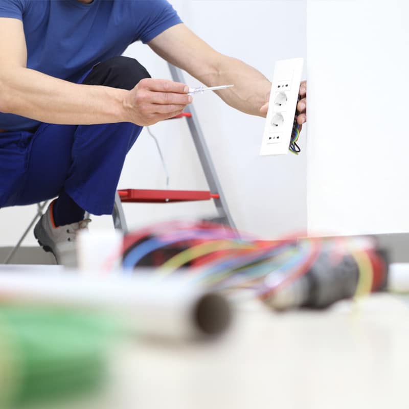 Electrician installing a new power outlet with tools and wiring visible, enhancing home electrical safety.