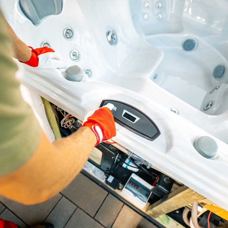 Person servicing a modern hot tub control panel, wearing red gloves for safety and precision work.