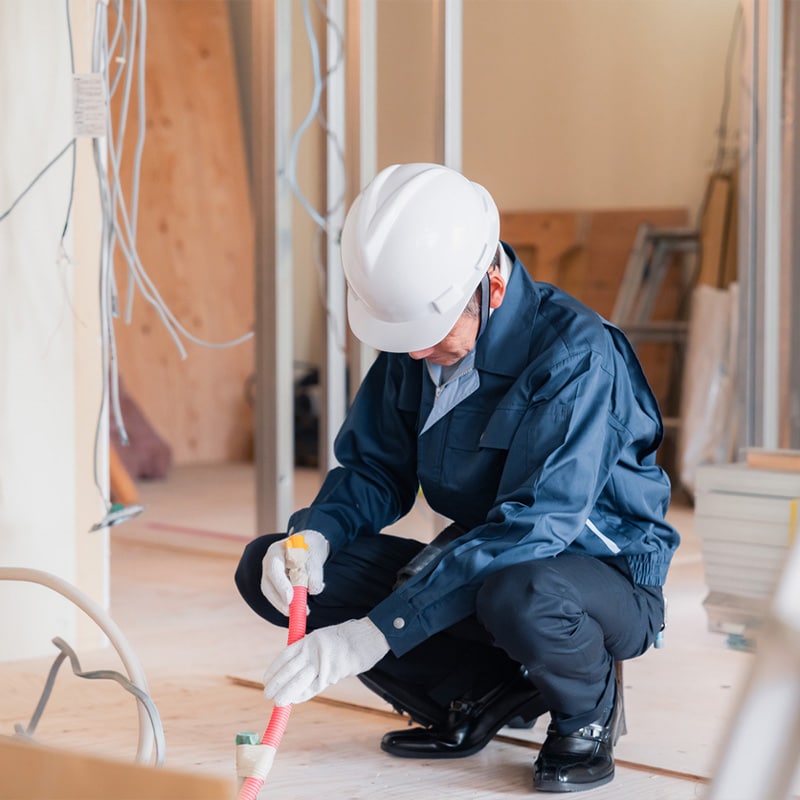 Builder in hard hat and uniform installing cables in a construction site.